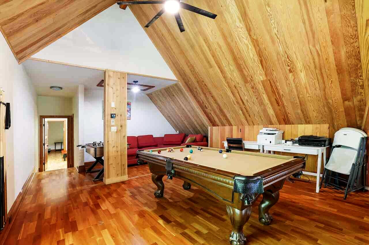 The game room with a billiards table set in the timber loft.