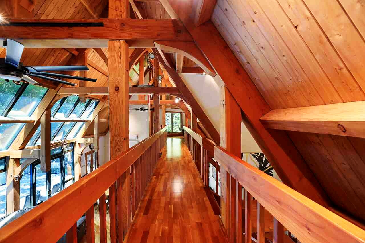 The mezzanine walkway running the long axis of the house beneath hand-carved timber trusses.