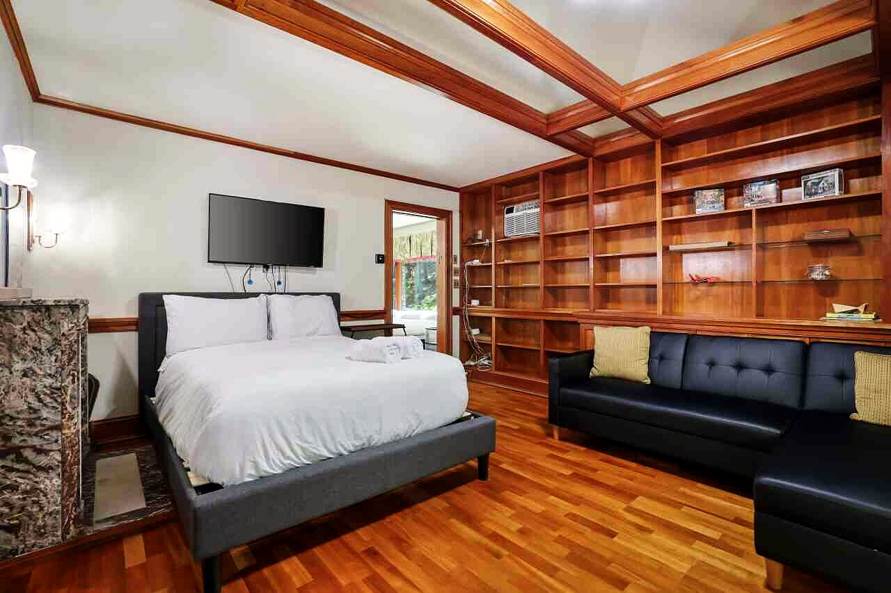 A bedroom lined with built-in bookshelves, with a sofa and a wall-mounted screen.